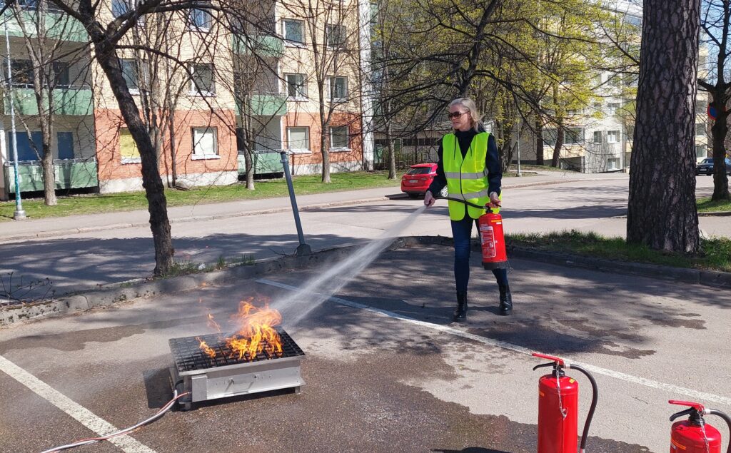 Henkilö opettelee sammuttimen käyttöä osana toimitilojen turvallisuutta.