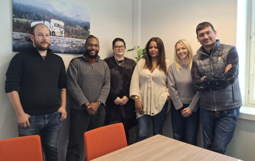 Kuusi Bulk Tainerin työntekijää pöydän takana seisomassa.