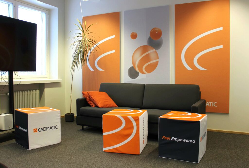 Cadmaticin toimitilamuutos Datariinassa. Kuvassa harmaa pieni sohva, jonka ympärillä oransseja sisustuselementtejä. 